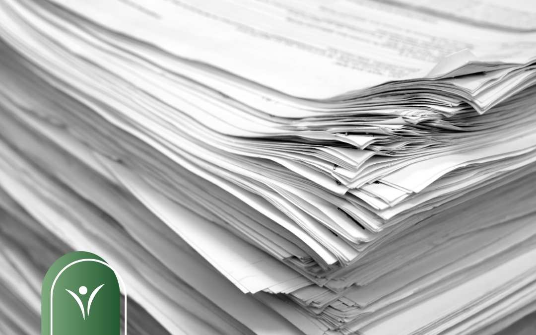 Stos dokumentów papierowych ułożonych jeden na drugim, symbolizujący formalności i dokumentację potrzebną do złożenia wniosku o świadczenie wspierające.