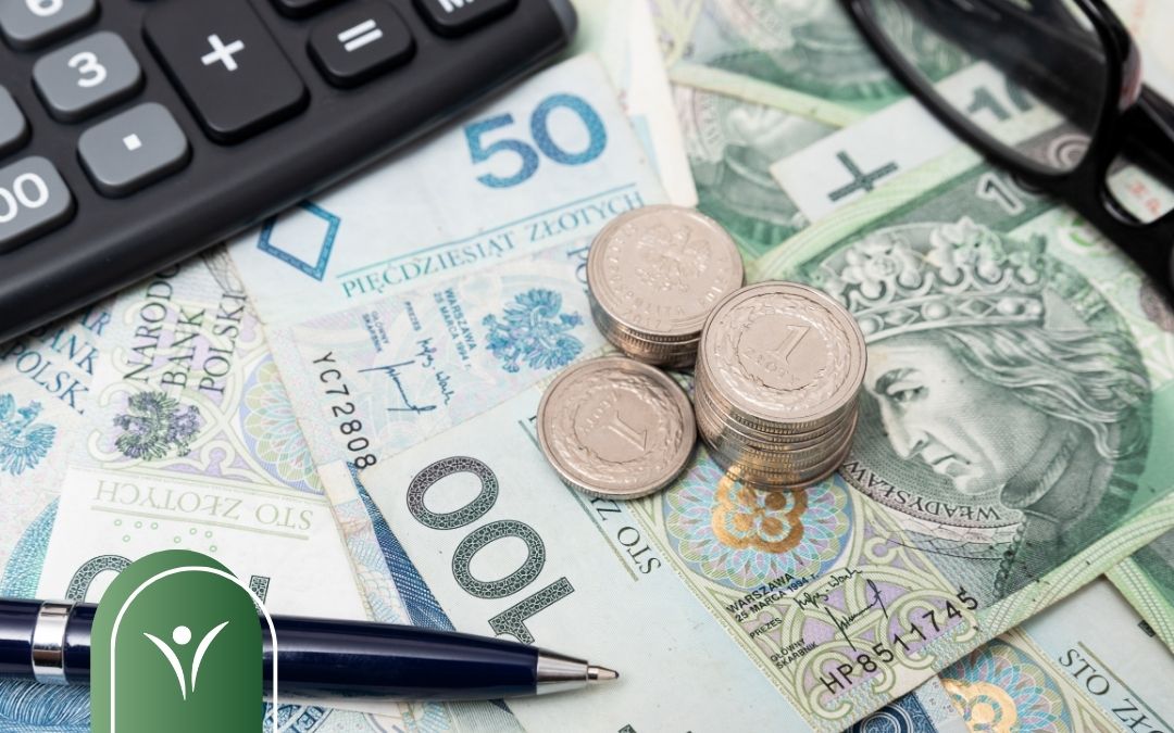 Banknoty i monety w złotych, kalkulator i długopis, symbolizujące wypłatę świadczenia oraz kwestie finansowe związane ze świadczeniem z ZUS.