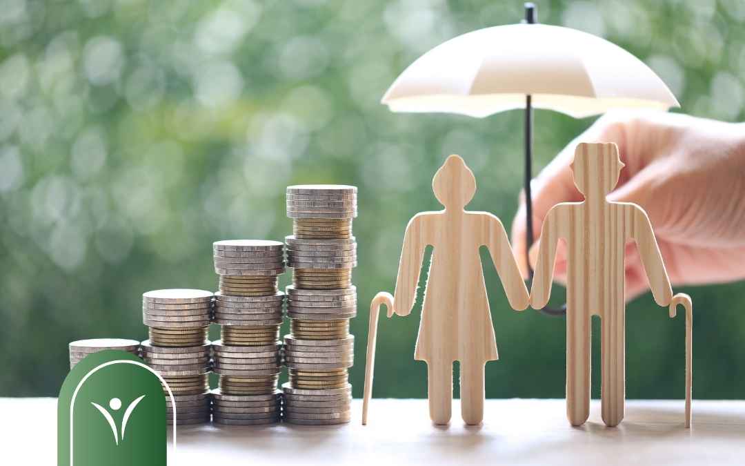 Drewniane figurki seniorów pod białym parasolem obok rosnących stosów monet.