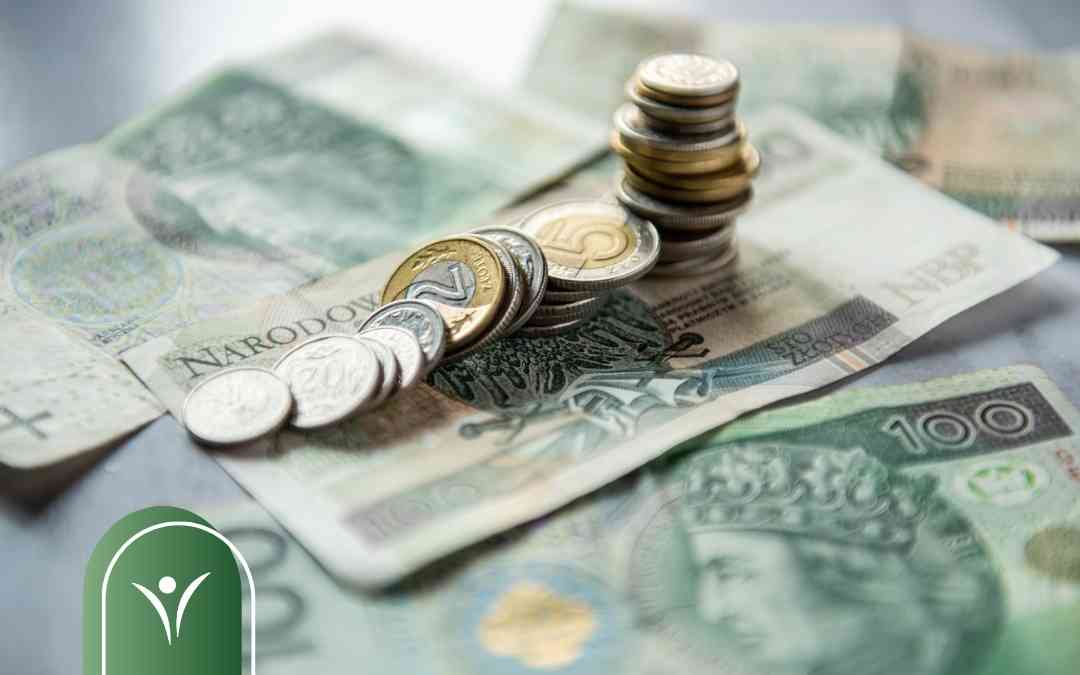 Polskie banknoty i stosy monet leżące na stole – symbol wysokości wsparcia finansowego dla osób z niepełnosprawnością