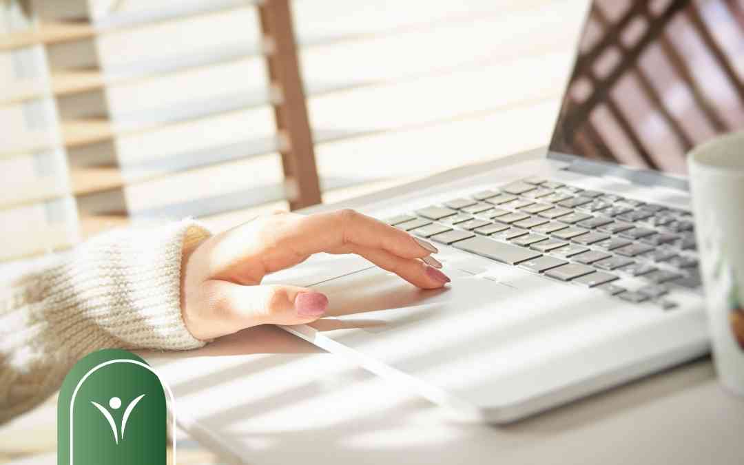 Dłoń na touchpadzie laptopa podczas wysyłania elektronicznego wniosku o świadczenie wspierające do ZUS