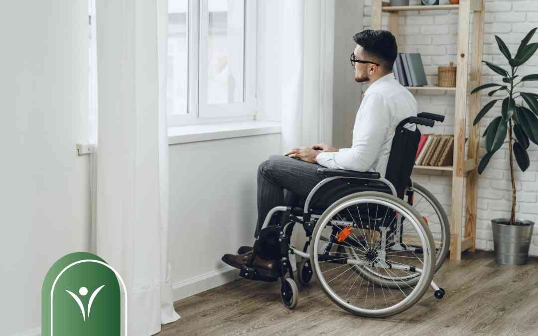 Mężczyzna na wózku inwalidzkim patrzący przez okno – ilustracja do artykułu o warunkach świadczenia wspierającego.