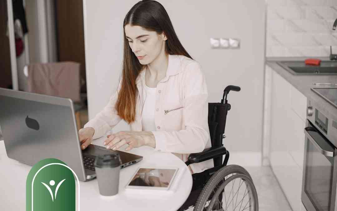 Młoda kobieta na wózku obsługuje laptopa, przygotowując elektroniczny wniosek o świadczenie wspierające do ZUS.