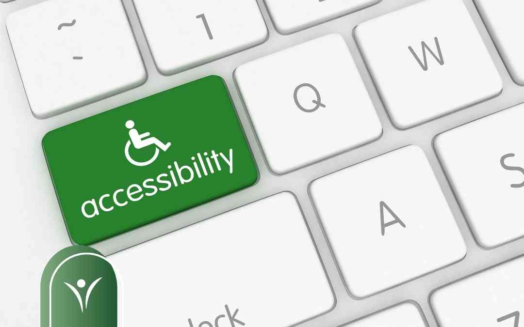 Klawiatura komputerowa z zielonym klawiszem accessibility i symbolem osoby na wózku inwalidzkim.
